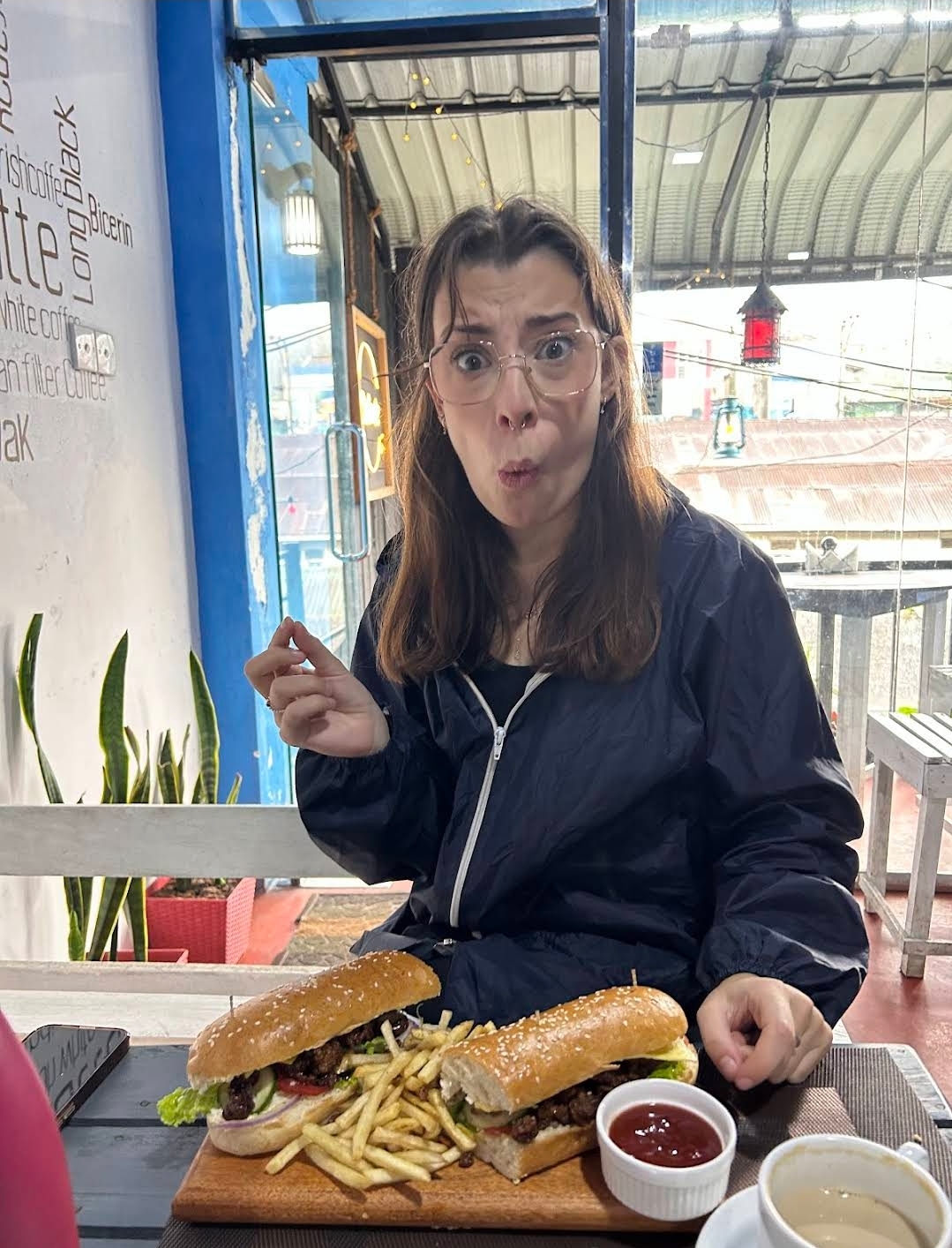 Guest reacting joyfully to a giant burger platter at Drizzle Café